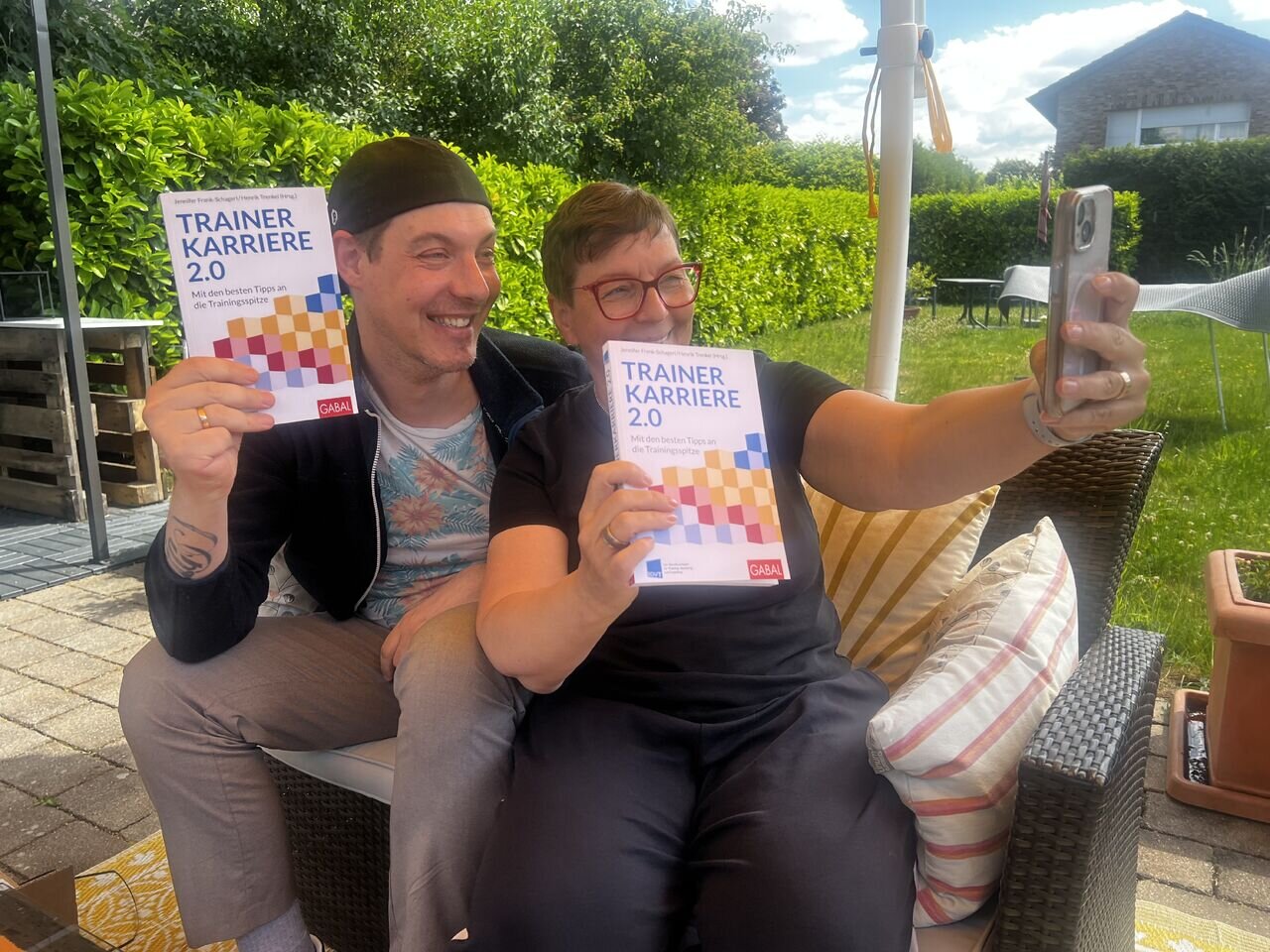 Timothy Tasch und Tanja Hartwig halten lachend je ein Exemplar des Buches „Trainerkarriere 2.0“ in die Kamera